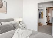 Thumbnail 25 of 47 - A bedroom with a bed, nightstand, and a closet with clothes at The Redwell Apartments, Minneapolis