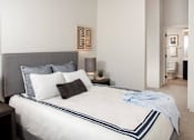 Thumbnail 27 of 47 - A bed with a white comforter and a blue striped border is in the foreground of a room at The Redwell Apartments, Minneapolis