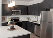 Thumbnail 36 of 47 - A modern kitchen with a stainless steel refrigerator and black cabinets at The Redwell Apartments, Minneapolis