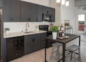 Thumbnail 38 of 47 - A kitchen with black cabinets and a white countertop at The Redwell Apartments, Minneapolis, MN