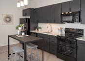 Thumbnail 40 of 47 - A kitchen with black cabinets and a black stove top oven at The Redwell Apartments, Minneapolis, 55401