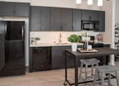 Thumbnail 41 of 47 - A black fridge and microwave in a kitchen with a table and stools at The Redwell Apartments, Minneapolis, Minnesota
