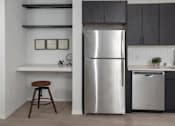 Thumbnail 42 of 47 - A kitchen with a stainless steel refrigerator and a bar stool at The Redwell Apartments, Minnesota