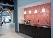 Thumbnail 46 of 47 - A modern kitchen with a red backsplash and wooden cabinets at The Redwell Apartments, Minnesota 55401