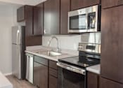 Thumbnail 19 of 54 - A modern kitchen with dark brown cabinets and stainless steel appliances.