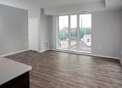 Thumbnail 23 of 54 - A room with a wooden floor and a large window overlooking a parking lot.