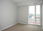 Thumbnail 25 of 54 - A room with a carpeted floor and a window overlooking a cityscape.