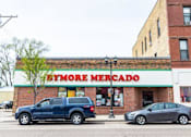 Thumbnail 42 of 54 - A blue car is parked in front of a store called Bymore Mercado.