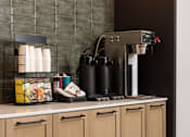 Thumbnail 17 of 55 - A coffee machine is on a counter with a stack of paper cups to its left.