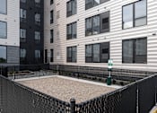Thumbnail 56 of 70 - A black fenced sandbox in front of apartment buildings.