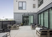 Thumbnail 58 of 70 - A patio with furniture and a building in the background.