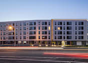 Thumbnail 69 of 70 - A modern building with a parking lot in front of it.
