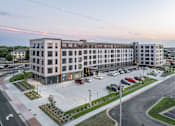 Thumbnail 63 of 70 - A large, modern building with a parking lot in front of it.