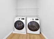 Thumbnail 50 of 55 - Two white front loading washing machines in a laundry room.