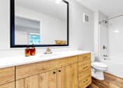 Thumbnail 38 of 113 - A white bathroom with a wooden vanity and a white toilet.