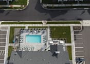 Thumbnail 96 of 113 - An aerial view of a parking lot with a pool and a building.