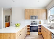 Thumbnail 14 of 49 - A modern kitchen with wooden cabinets and a white countertop.