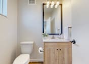 Thumbnail 12 of 49 - A white toilet sits next to a wooden cabinet with a mirror above it.