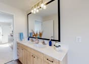 Thumbnail 7 of 49 - A bathroom with a vanity, mirror, and a bedroom in the background.