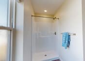 Thumbnail 8 of 49 - A blue towel is hanging on a white wall next to a glass shower door.