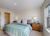 Thumbnail 10 of 49 - A bedroom with a bed, nightstand, and window.