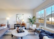 Thumbnail 5 of 49 - A modern living room with a grey sofa, a coffee table, and a large window.