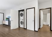 Thumbnail 67 of 104 - a washer and dryer in a living room with a door to a bathroom