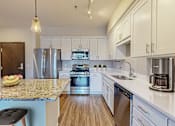 Thumbnail 57 of 104 - A kitchen with a granite countertop and stainless steel appliances.