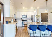 Thumbnail 26 of 104 - A kitchen with white appliances and blue chairs.