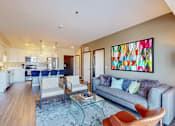 Thumbnail 28 of 104 - A modern living room with a grey couch and a painting on the wall.