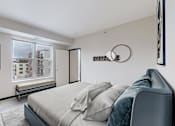 Thumbnail 41 of 104 - A bedroom with a bed, a chair, and a window overlooking a building.