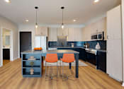 Thumbnail 38 of 64 - A kitchen with a blue island and orange chairs.