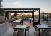 Thumbnail 59 of 64 - A patio with tables and chairs is set up under a pergola.