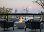 Thumbnail 61 of 64 - A fire pit sits in the middle of a patio surrounded by chairs.