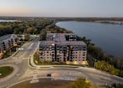 Thumbnail 63 of 64 - A large building is situated on a road with a body of water in the background.