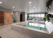 Thumbnail 22 of 64 - A modern indoor swimming pool with a wooden door and a glass wall.