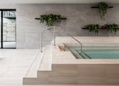 Thumbnail 23 of 64 - A modern indoor swimming pool with a glass enclosure and a wooden ledge.