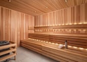 Thumbnail 24 of 64 - A wooden sauna with benches and lights.