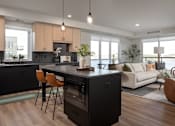 Thumbnail 25 of 64 - A modern kitchen with a black island and wooden floors.