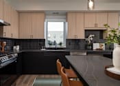 Thumbnail 26 of 64 - A kitchen with black countertops and wooden cabinets.