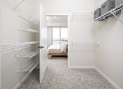 Thumbnail 33 of 64 - A white walk-in closet with shelves and a doorway leading to a living room.