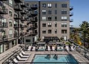 Thumbnail 45 of 64 - A large apartment complex with a pool and lounge chairs.