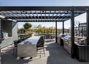 Thumbnail 46 of 64 - A patio with a table and chairs under a roof.