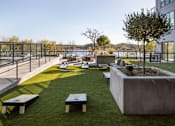 Thumbnail 47 of 64 - A modern outdoor seating area with concrete planters and benches overlooking a body of water.
