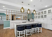Thumbnail 2 of 102 - A kitchen with white cabinets and a bar area with blue stools.