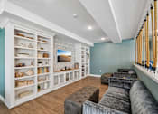 Thumbnail 4 of 102 - A living room with a white bookcase and a grey couch.