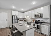 Thumbnail 88 of 102 - A modern kitchen with white cabinets and stainless steel appliances.