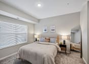 Thumbnail 93 of 102 - A bedroom with a large bed and a nightstand with a lamp.