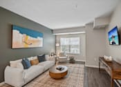 Thumbnail 90 of 102 - A living room with a white couch and a painting on the wall.