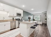 Thumbnail 57 of 91 - A kitchen with white cabinets and a wooden island.